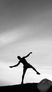 silhouette of person balancing on edge at sunset
